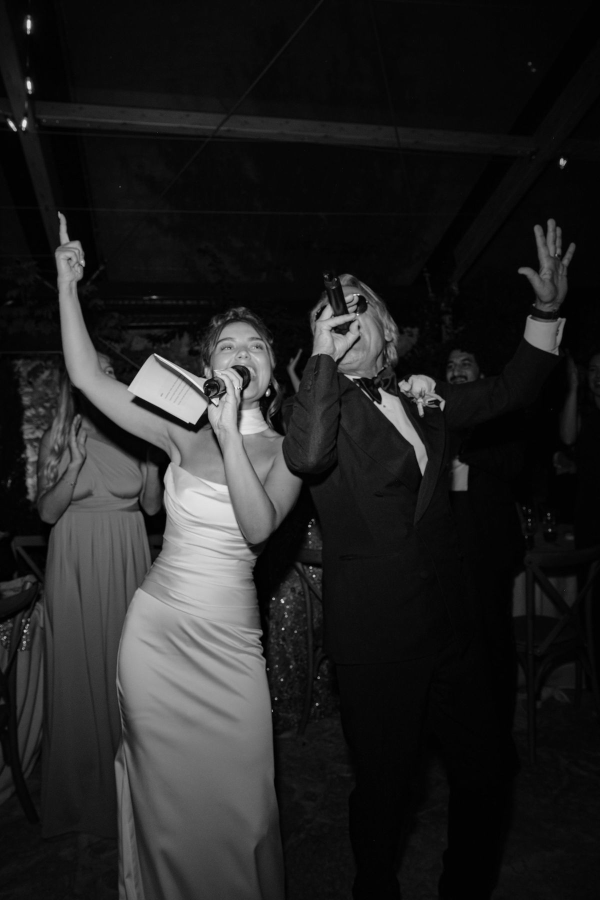 Bride singing with arms raised during indoor reception celebration