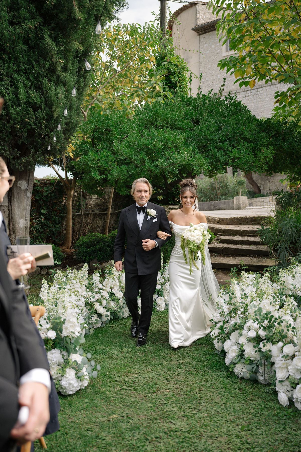Bride walking down floral aisle with her father at outdoor ceremony
