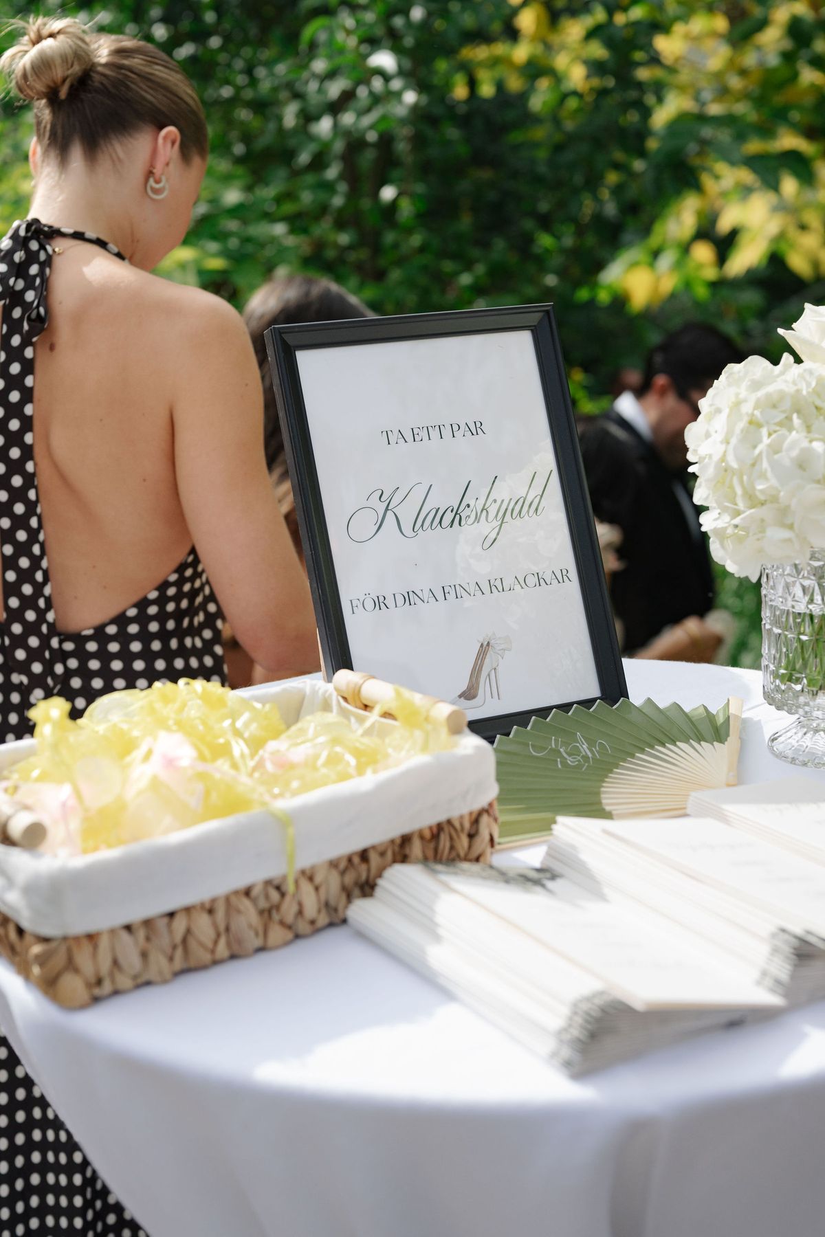 Favour table with framed sign, paper fans, and hydrangea arrangement