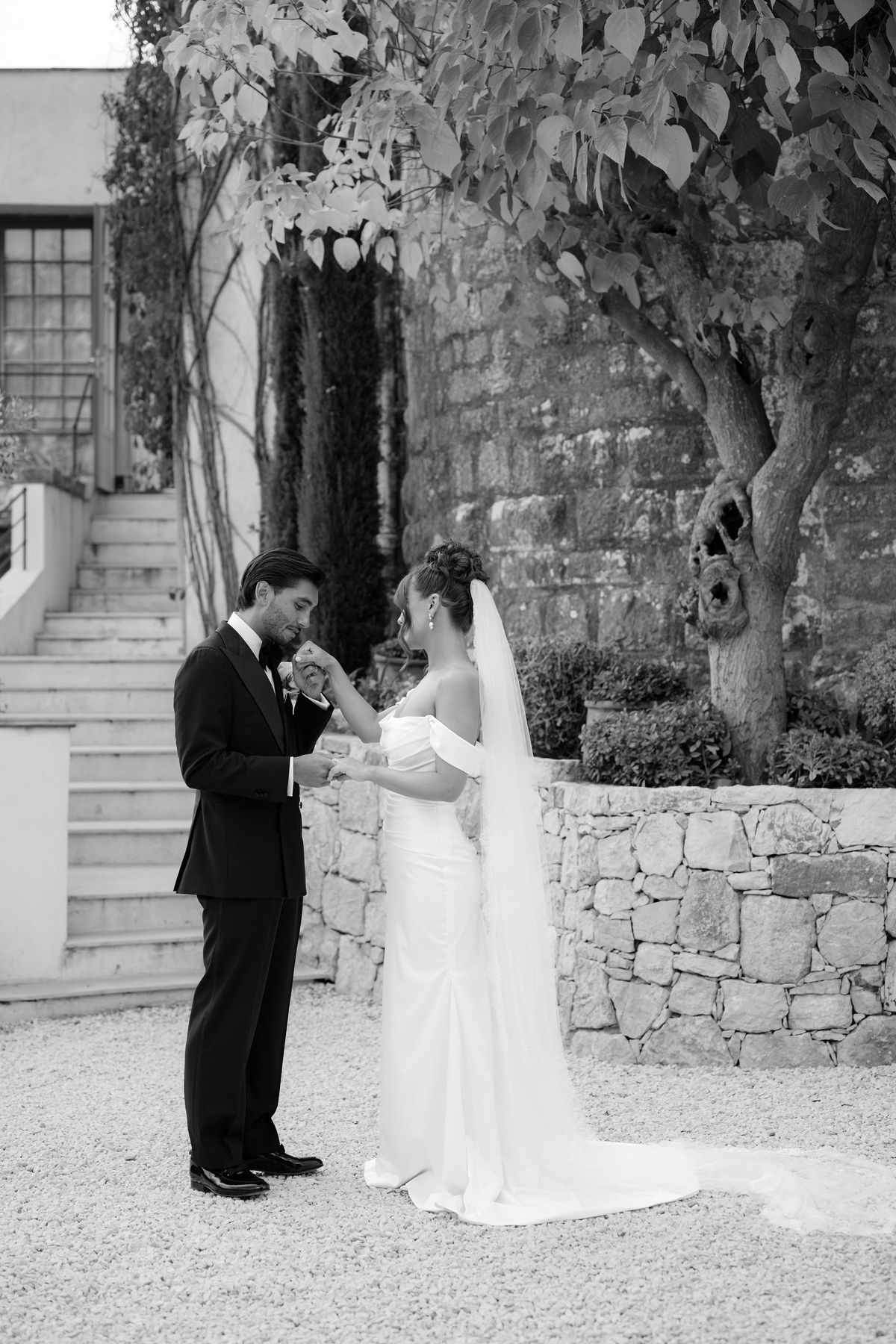 Groom kissing bride's hand during private first look in courtyard