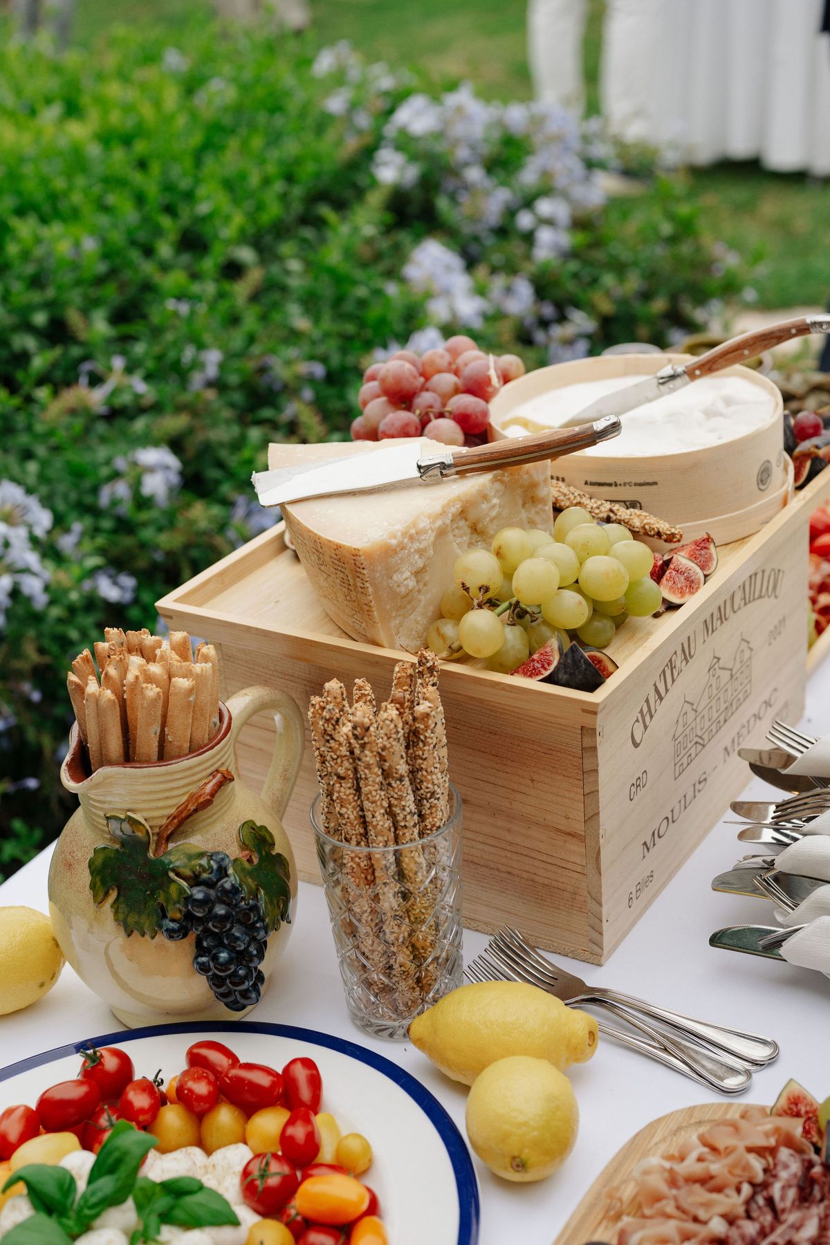 Antipasti buffet table with cheese, figs, grapes, and grissini in garden