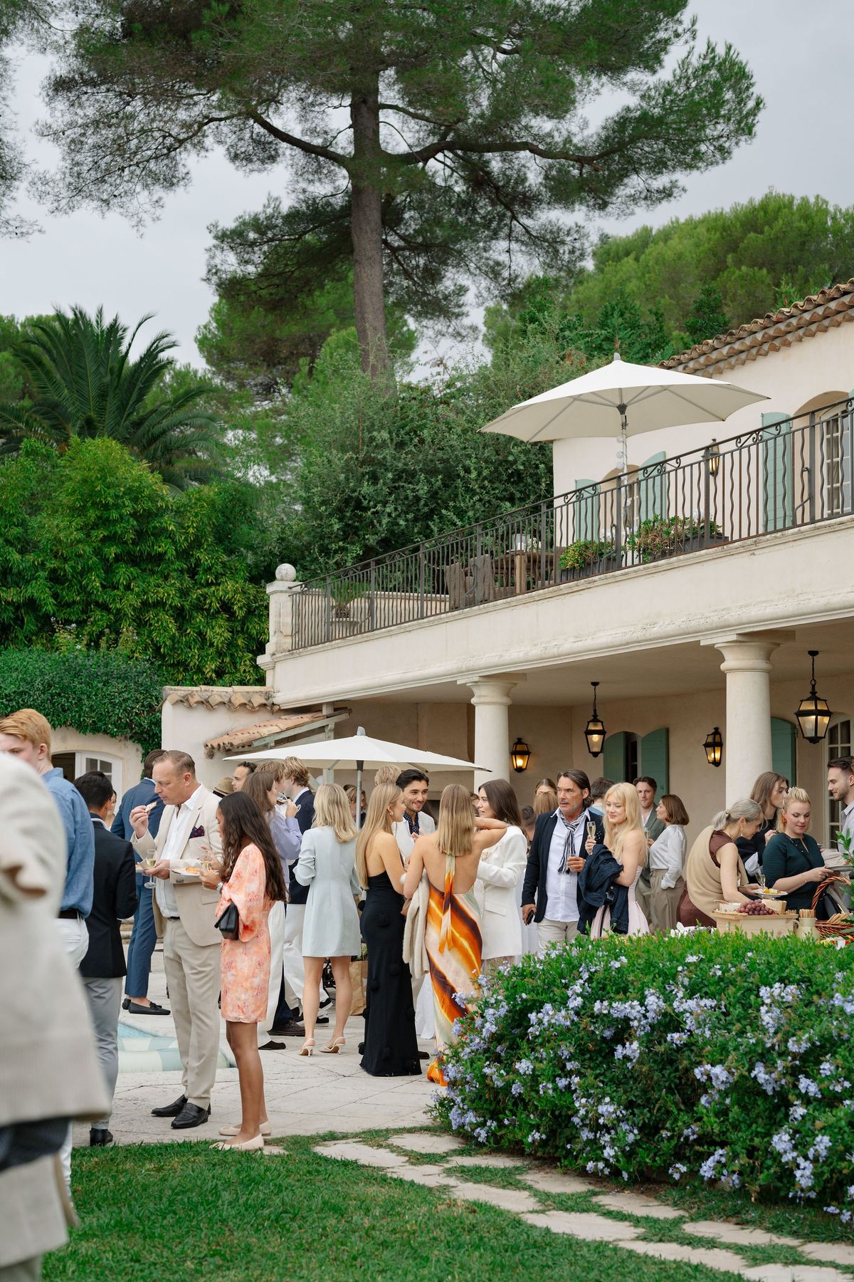 Guests mingling at outdoor cocktail hour beside Provencal yellow villa