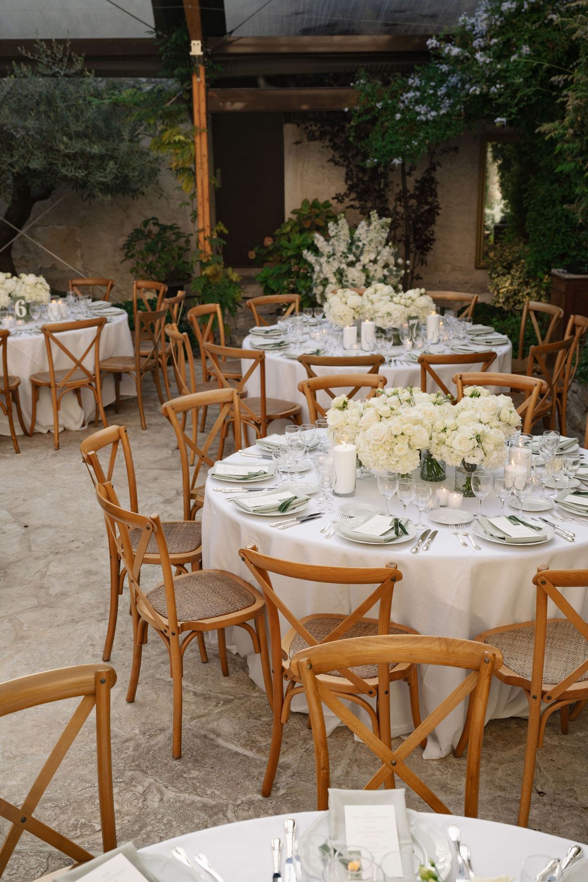 Marquee reception with white floral tables and natural wood chairs