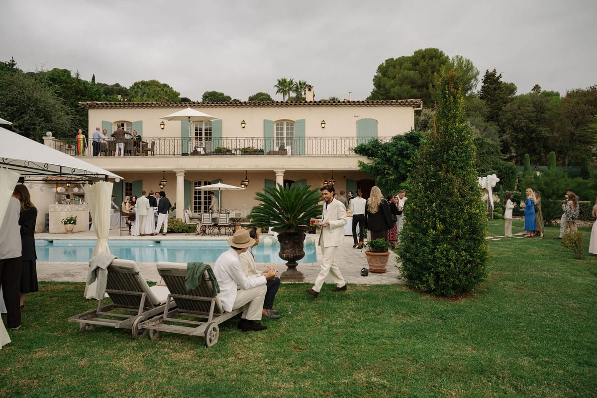 Pale Provencal villa with pool and cocktail hour guests on terrace