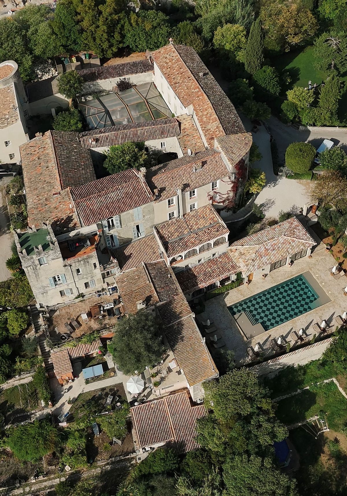 Aerial detail of chateau rooftops, checkerboard pool, and marquee