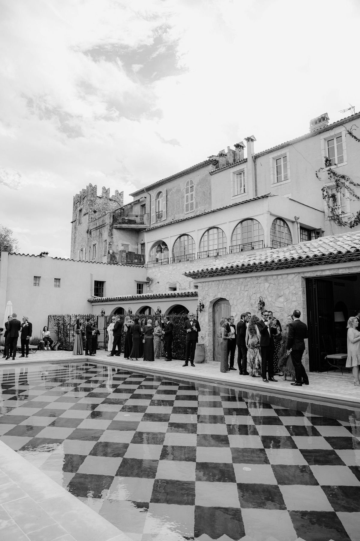 Black and white view of checkerboard pool and stone chateau facade