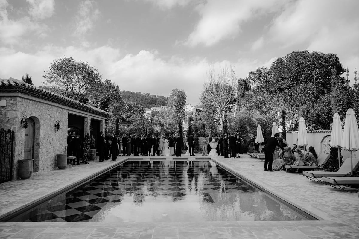 Black and white view of long checkerboard pool with cocktail guests
