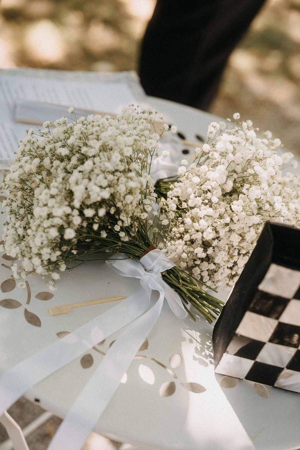 Two baby's breath bouquets tied with sheer white ribbon on decorative metal table