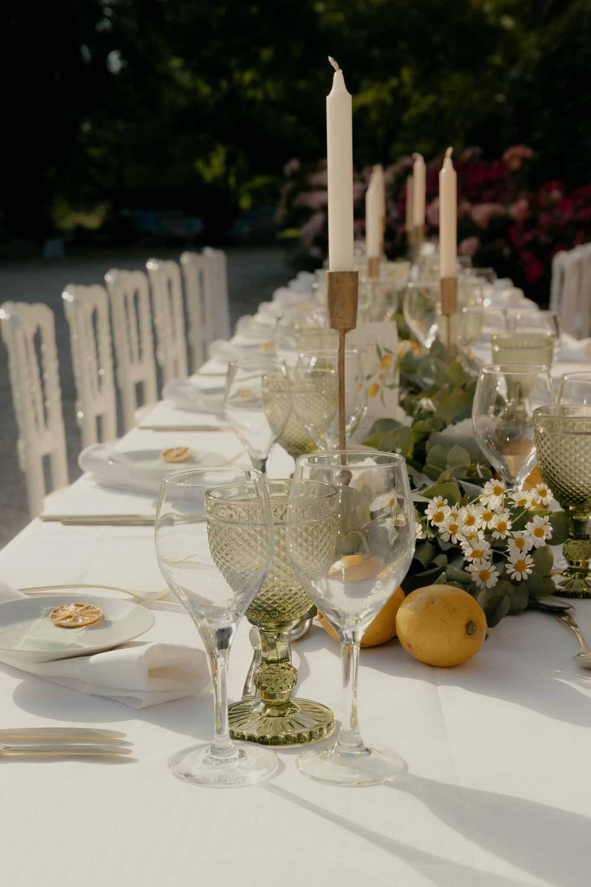 Reception table with eucalyptus garland lemons ivory taper candles sage green goblets and gold flatware