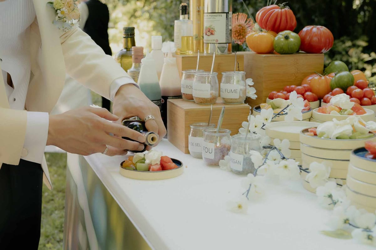 Gourmet tomato bar station with heirloom tomatoes, artisan salts, olive oil, and white blossom branches