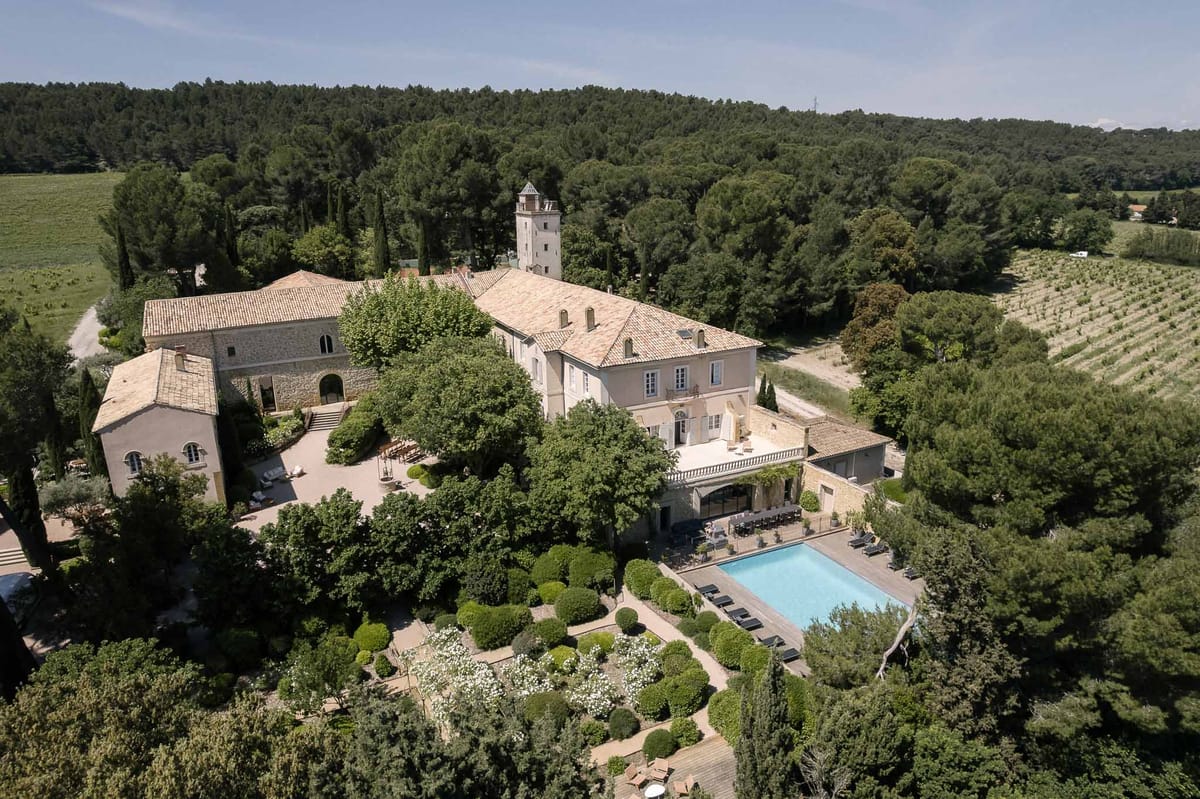 Aerial view of Provencal chateau with pool terrace, topiary garden, courtyard, and vineyard rows