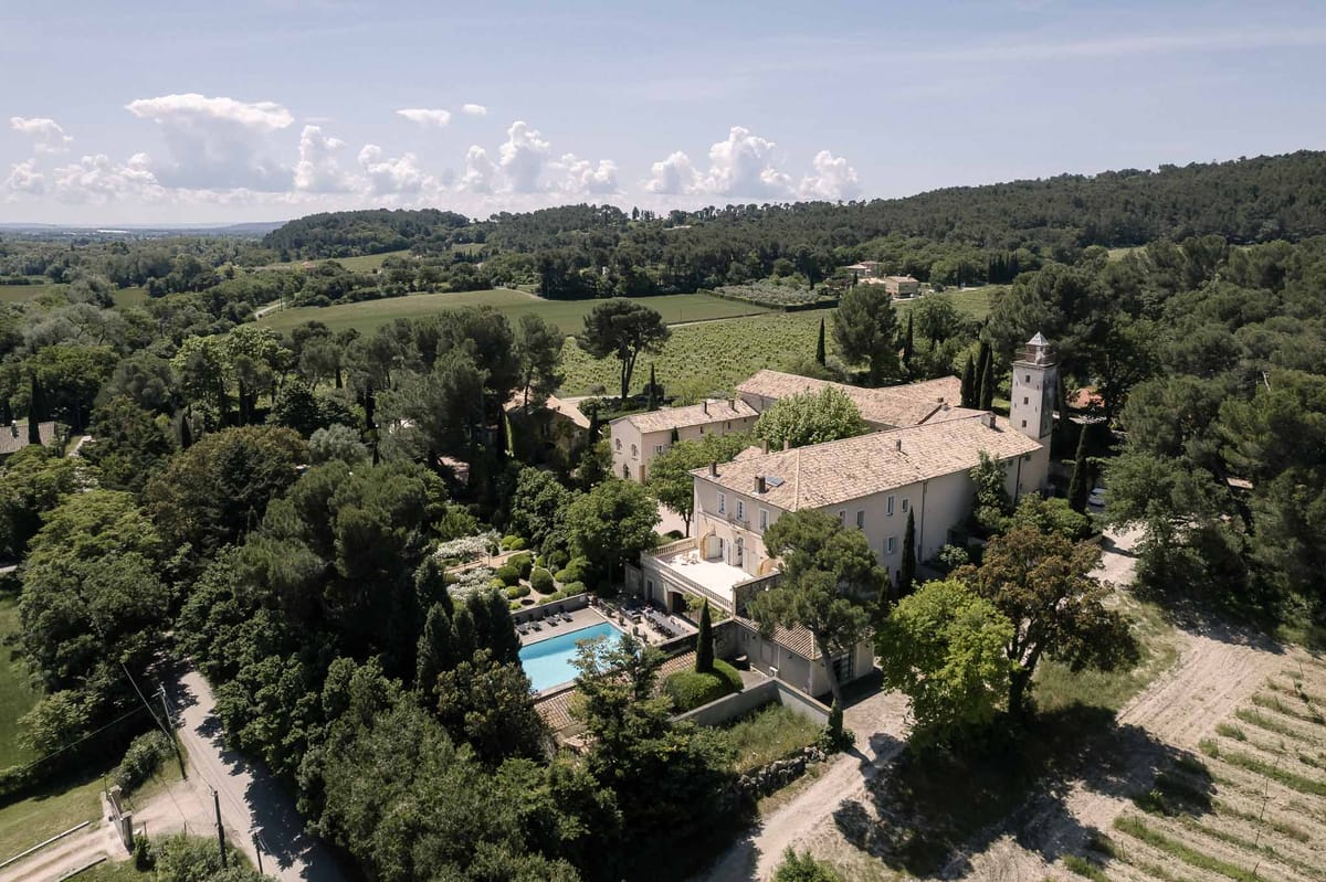 Aerial chateau estate with square tower turquoise pool box hedging vineyards and rolling countryside