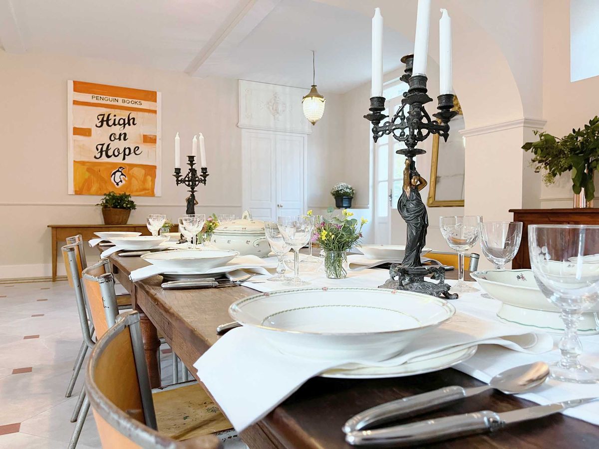 Rustic wooden table with bronze candelabras wildflower bud vases and green-rimmed china in eclectic room