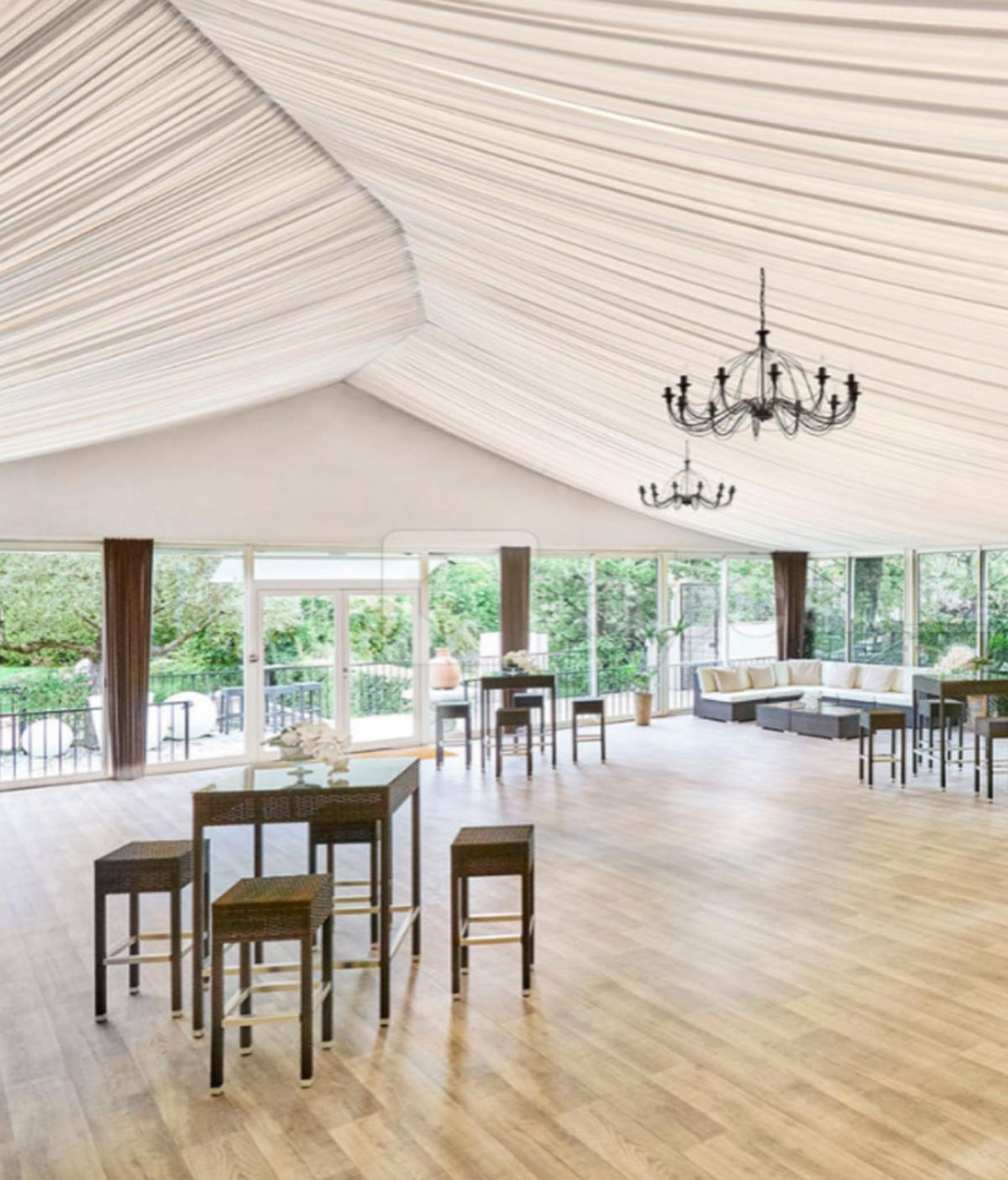 White marquee with iron chandeliers, dark rattan cocktail tables, and cream sectional lounge area