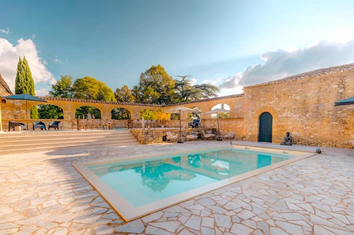 Stone property with rectangular pool, flagstone terrace, and upper stone arcade with arches