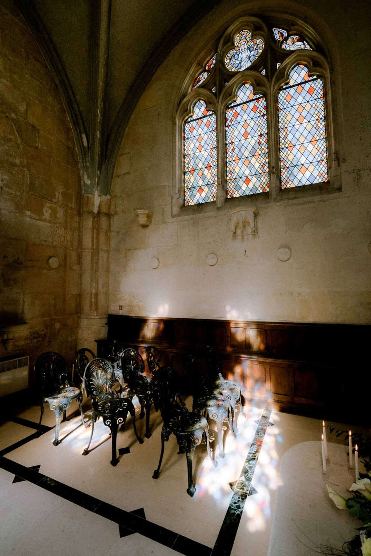 Gothic chapel interior with stained glass lancet windows casting colored light on marble floor