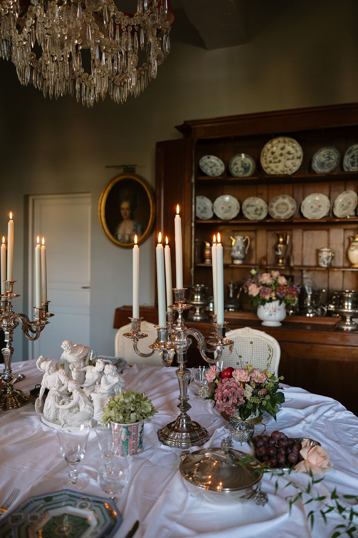 Silver candelabras and pink carnation arrangements beside transferware display in chateau dining room