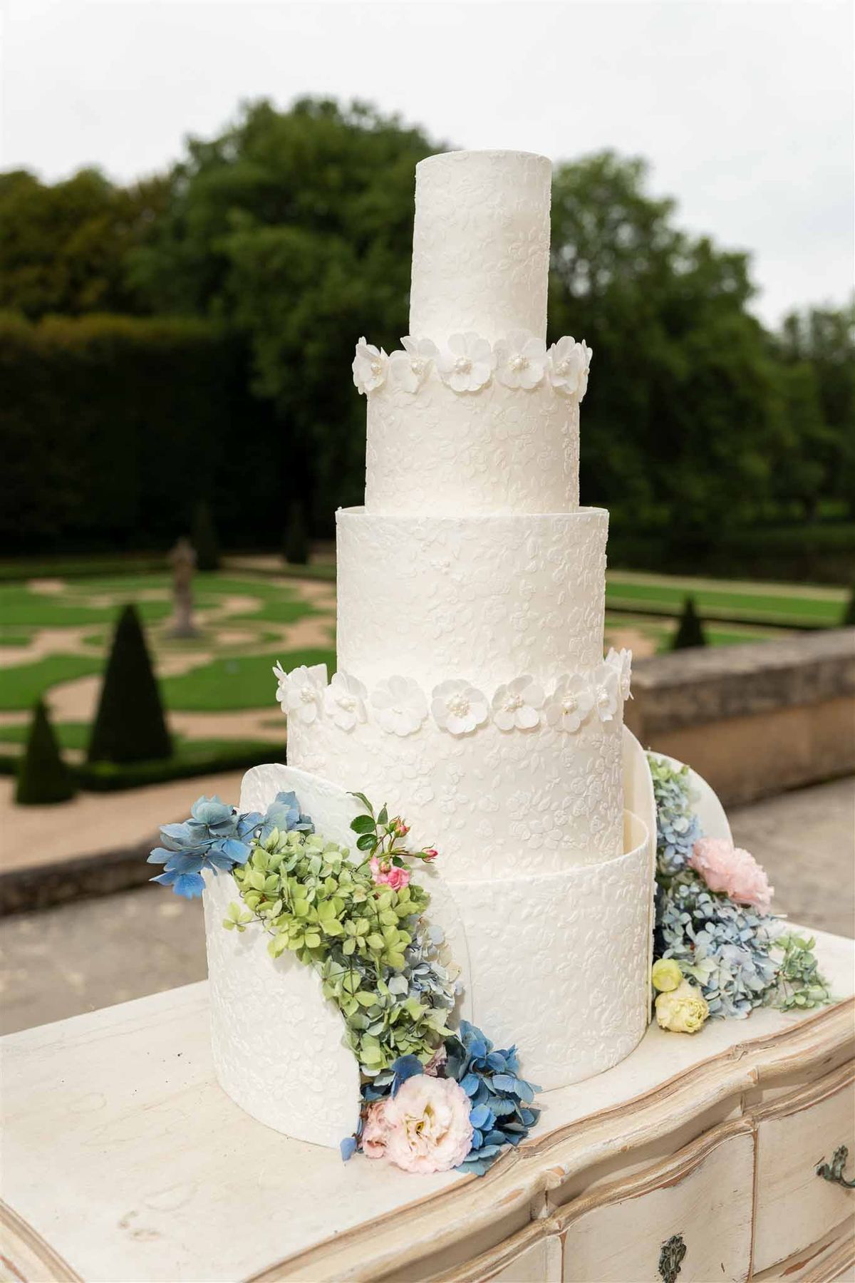 Close-up of white wedding cake with pastel flowers at Chateau de Villette