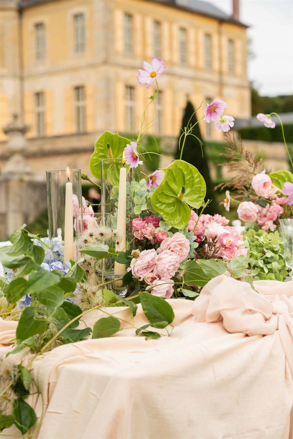 Pink floral centrepiece with chateau behind at Chateau de Villette