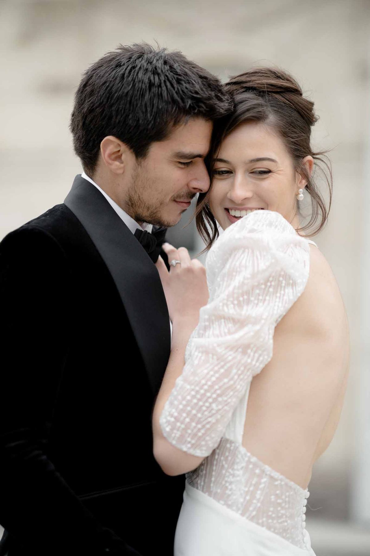 View of bride's open-back sparkly dress as groom embraces her