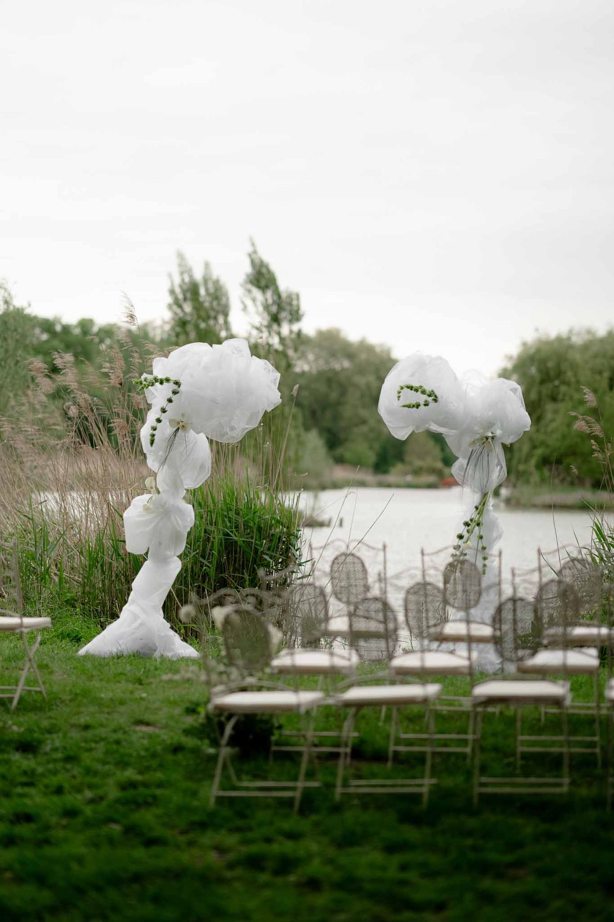 Outdoor ceremony setup beside the lake at Chateau d'Arcelot with floral arch and seating