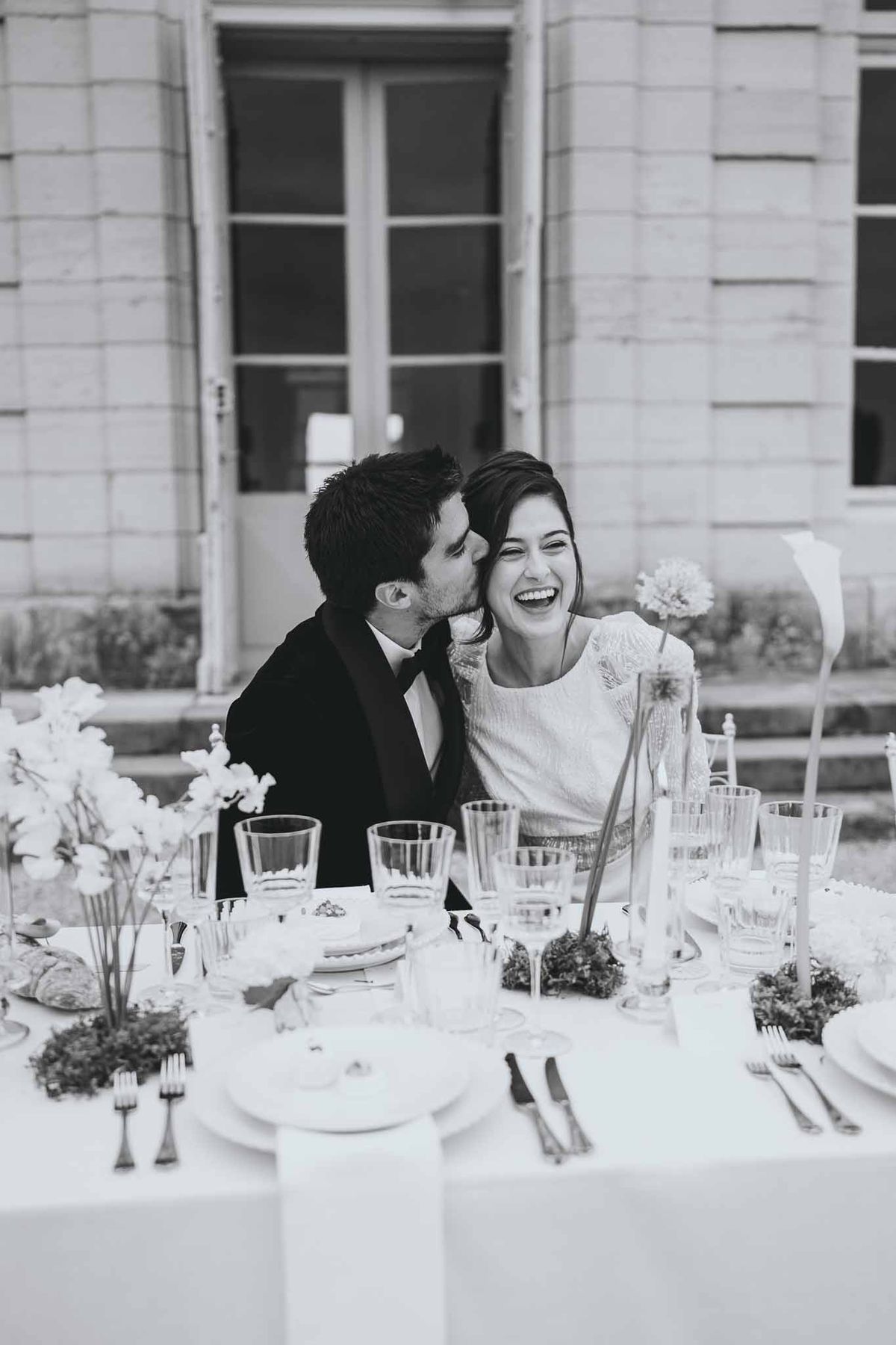 Couple sharing a kiss while seated at the reception table