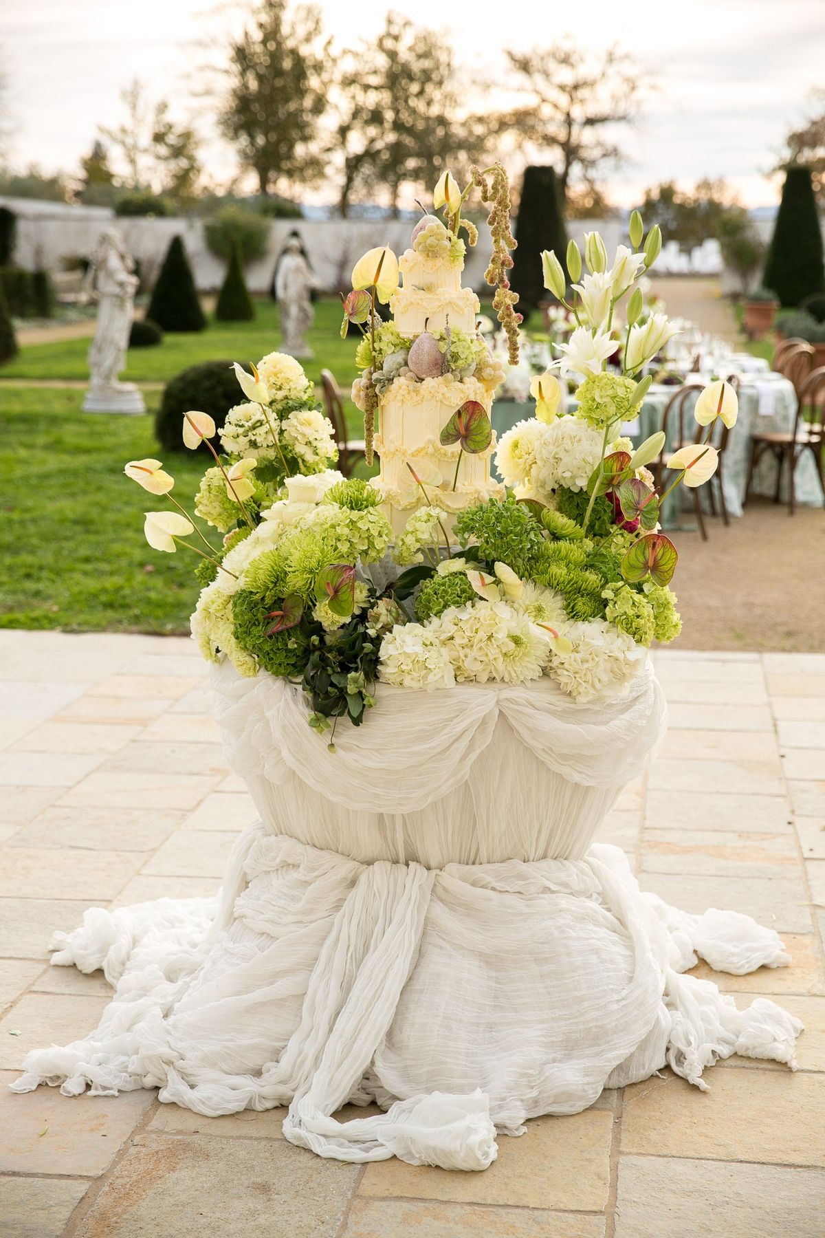 Twilight view of a floral cake plinth with anthuriums and hydrangeas surrounding a tiered cake