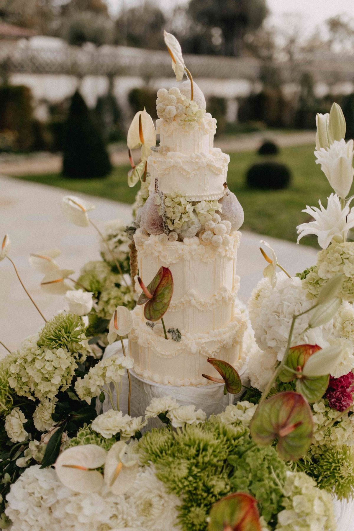 Macro detail of cake tier piping with anthurium blooms tucked into the icing