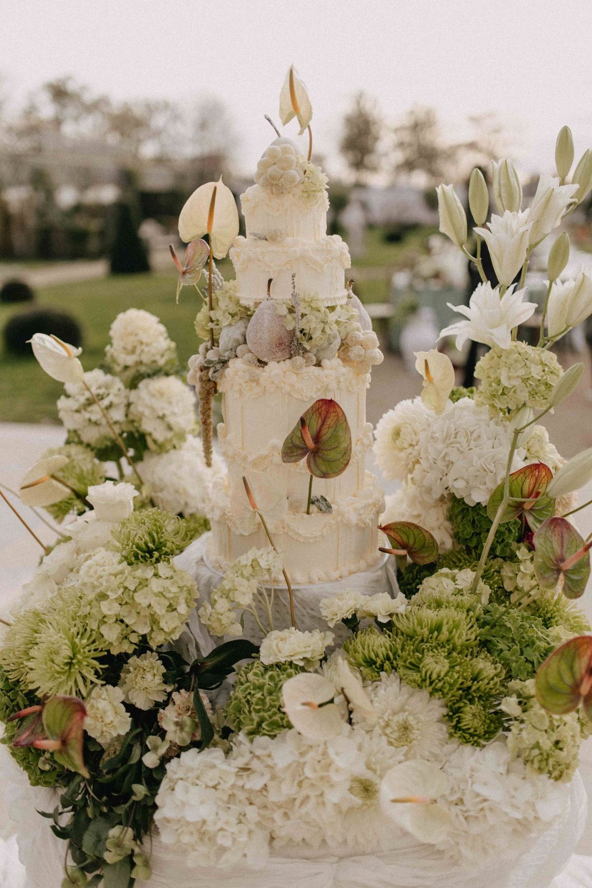 Piped cake on a floral plinth with lilies and anthuriums fanning out in the garden