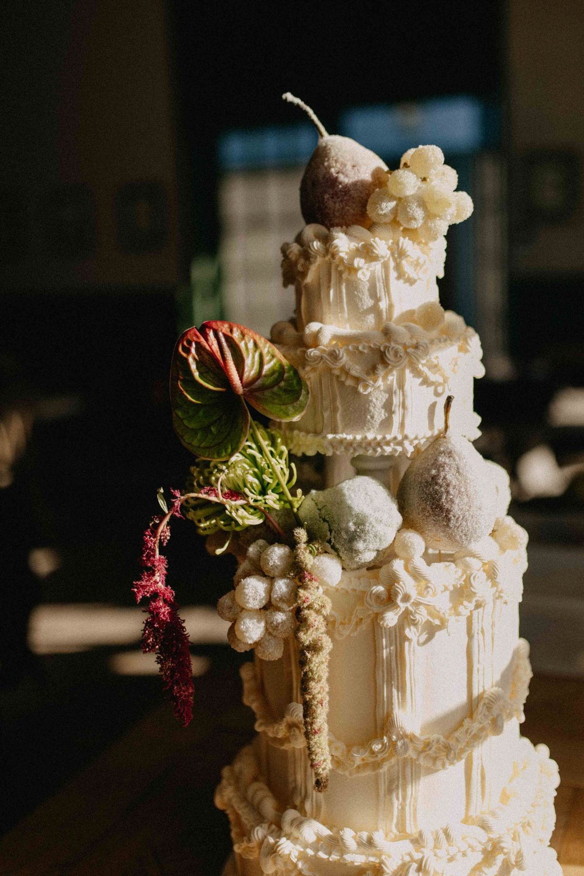 Architectural side view of a piped tiered cake with miniature columns and raking sunlight