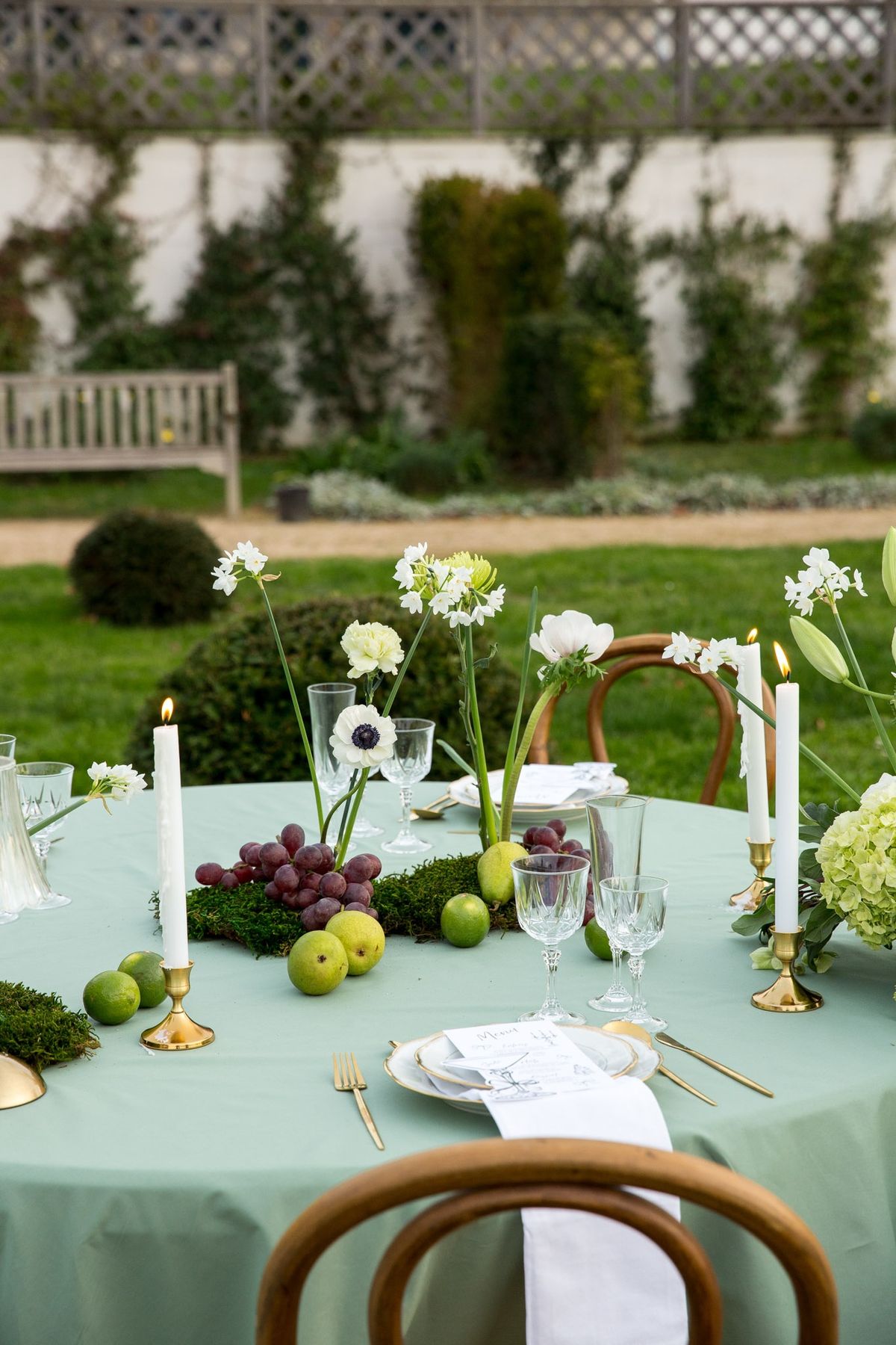 Two adjoining round tables with fluted glass lamp, grapes, limes, pears and florals