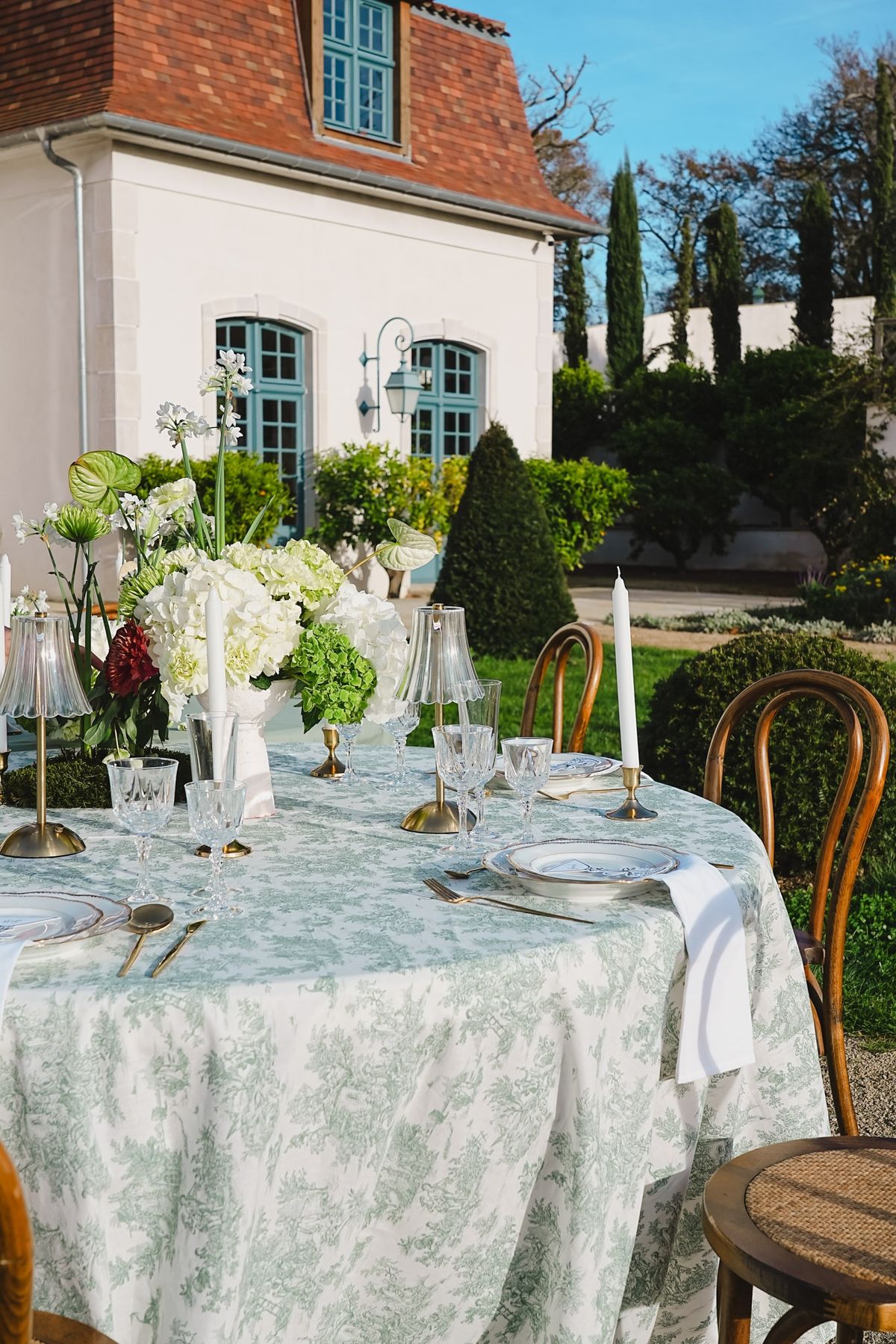 Tablescape against the chateau facade with hydrangea centerpiece, crystal stemware and bistro chairs