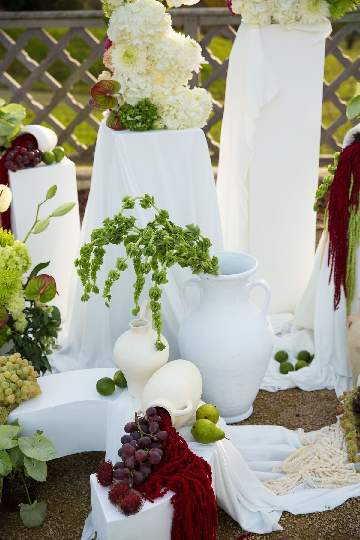 Detail of ceremony pillars with hydrangea towers, ceramic vessels and grapes piled below