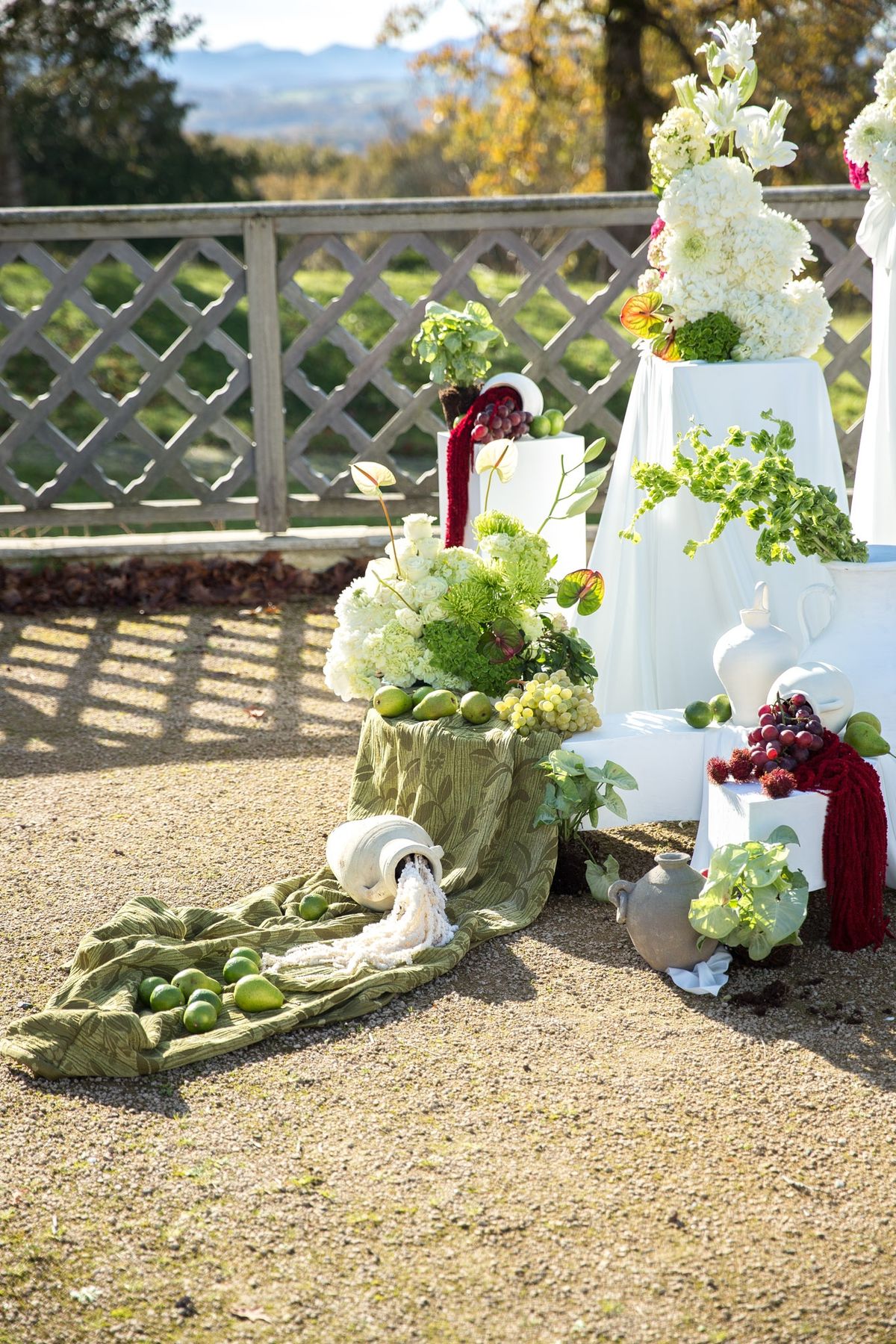Lower detail of backdrop with tipped white urn, green textile and hydrangea on white plinth