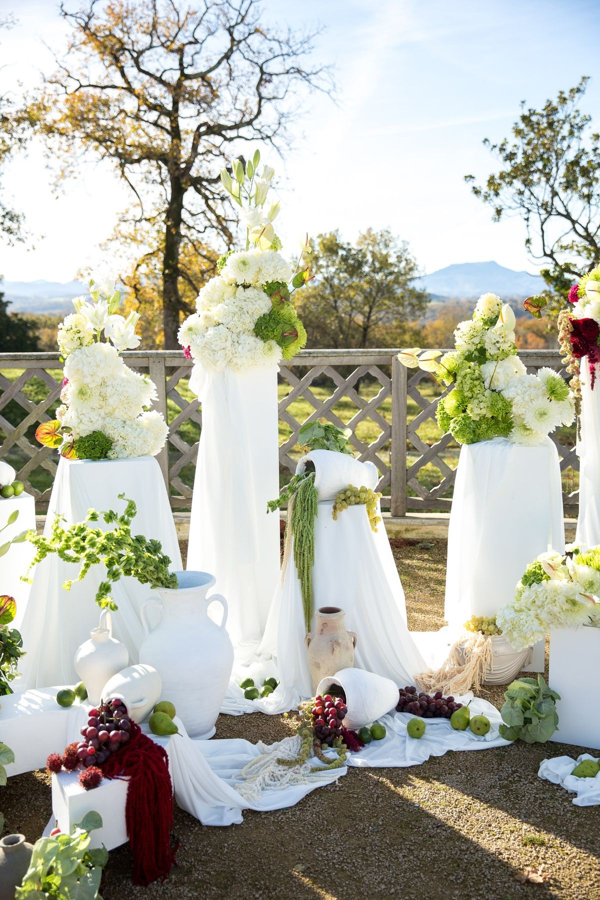 Golden hour ceremony backdrop with hydrangea towers atop white plinths in the chateau garden