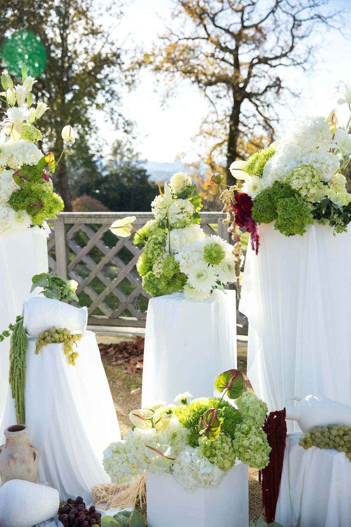 Ceremony backdrop florals with anthurium leaves, hydrangeas and fluted glass urn at the plinth foot