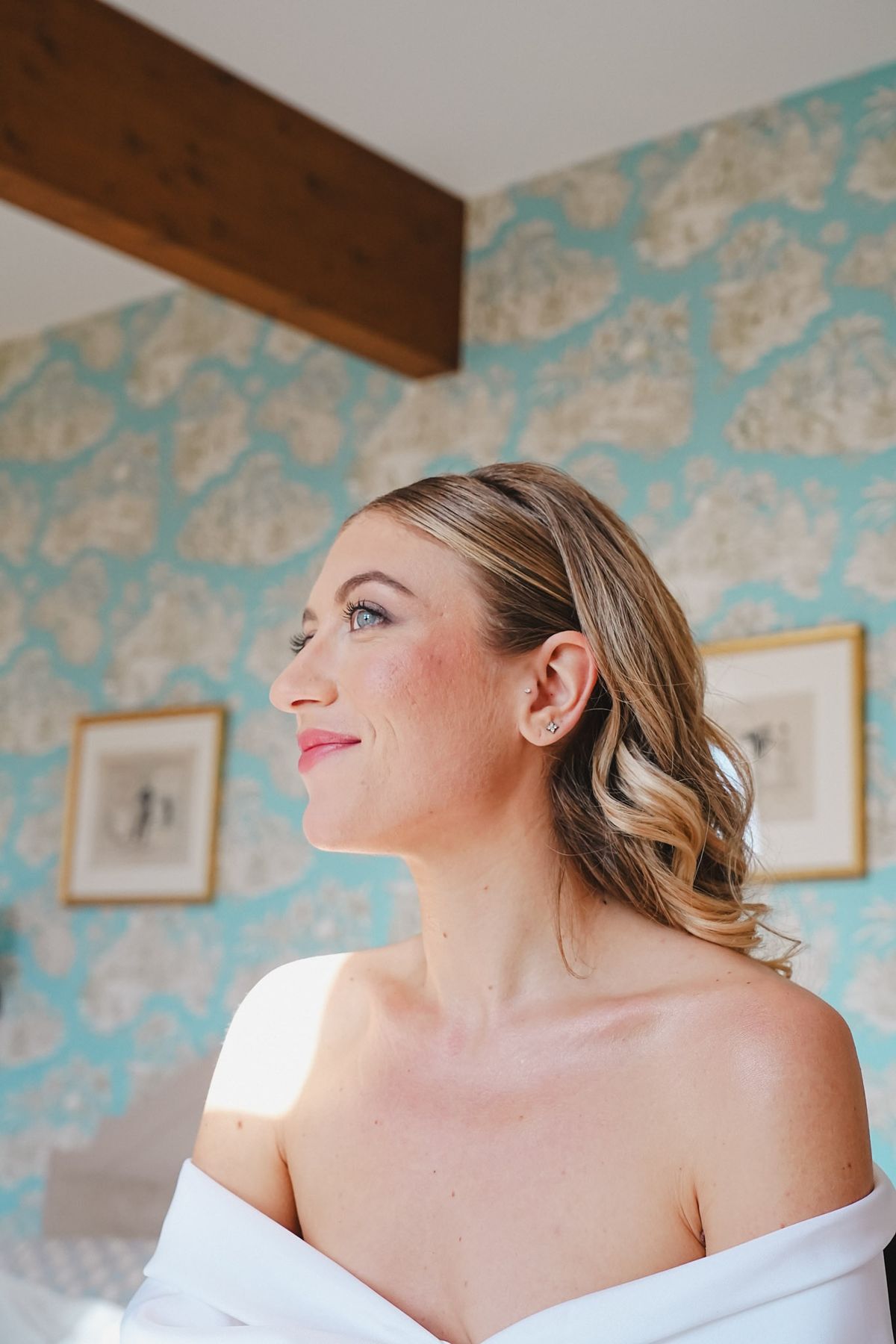Bride profile portrait in soft makeup against turquoise toile wallpaper with gilded frames