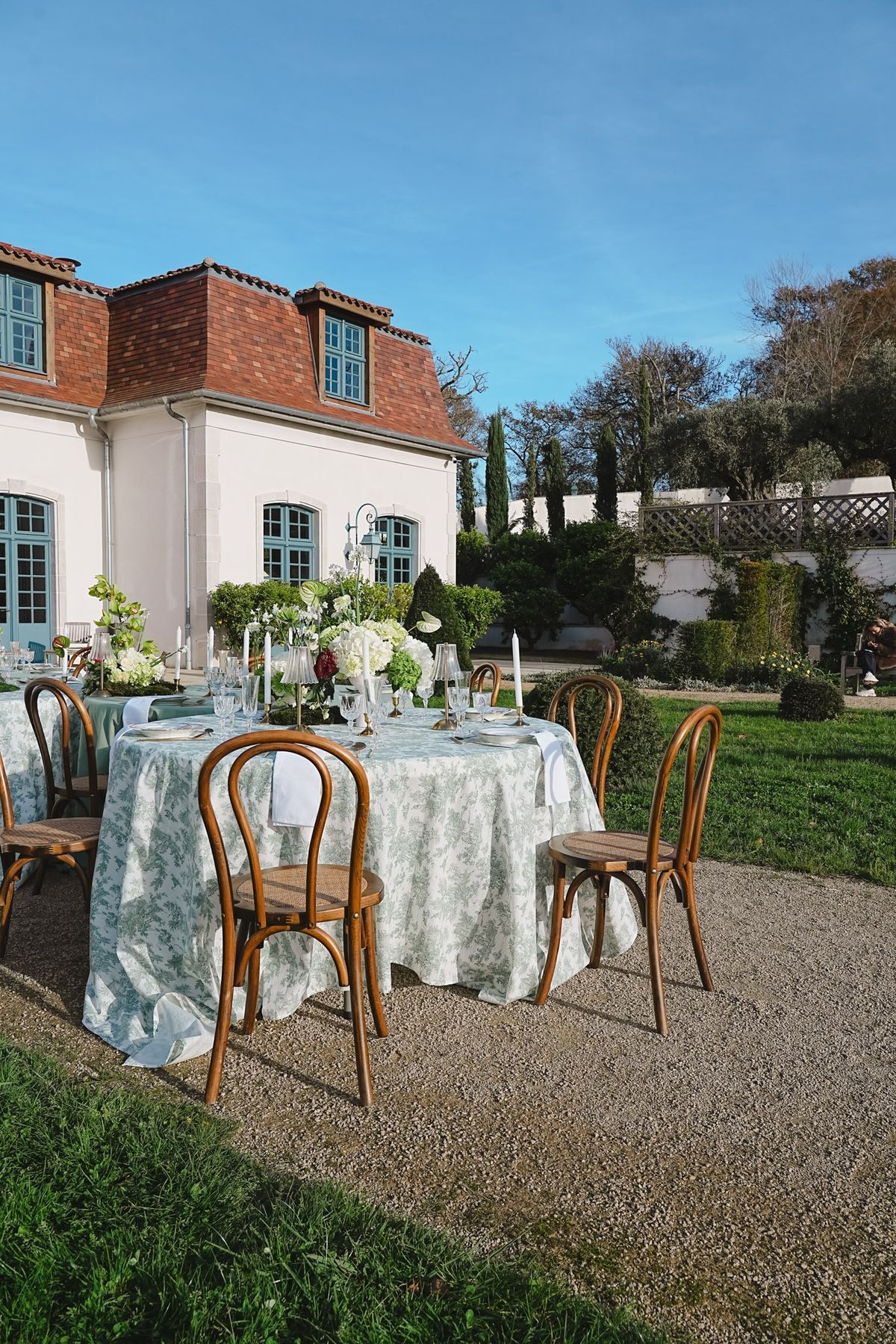Toile dressed reception tables on chateau terrace with cream pavilion and red roof behind