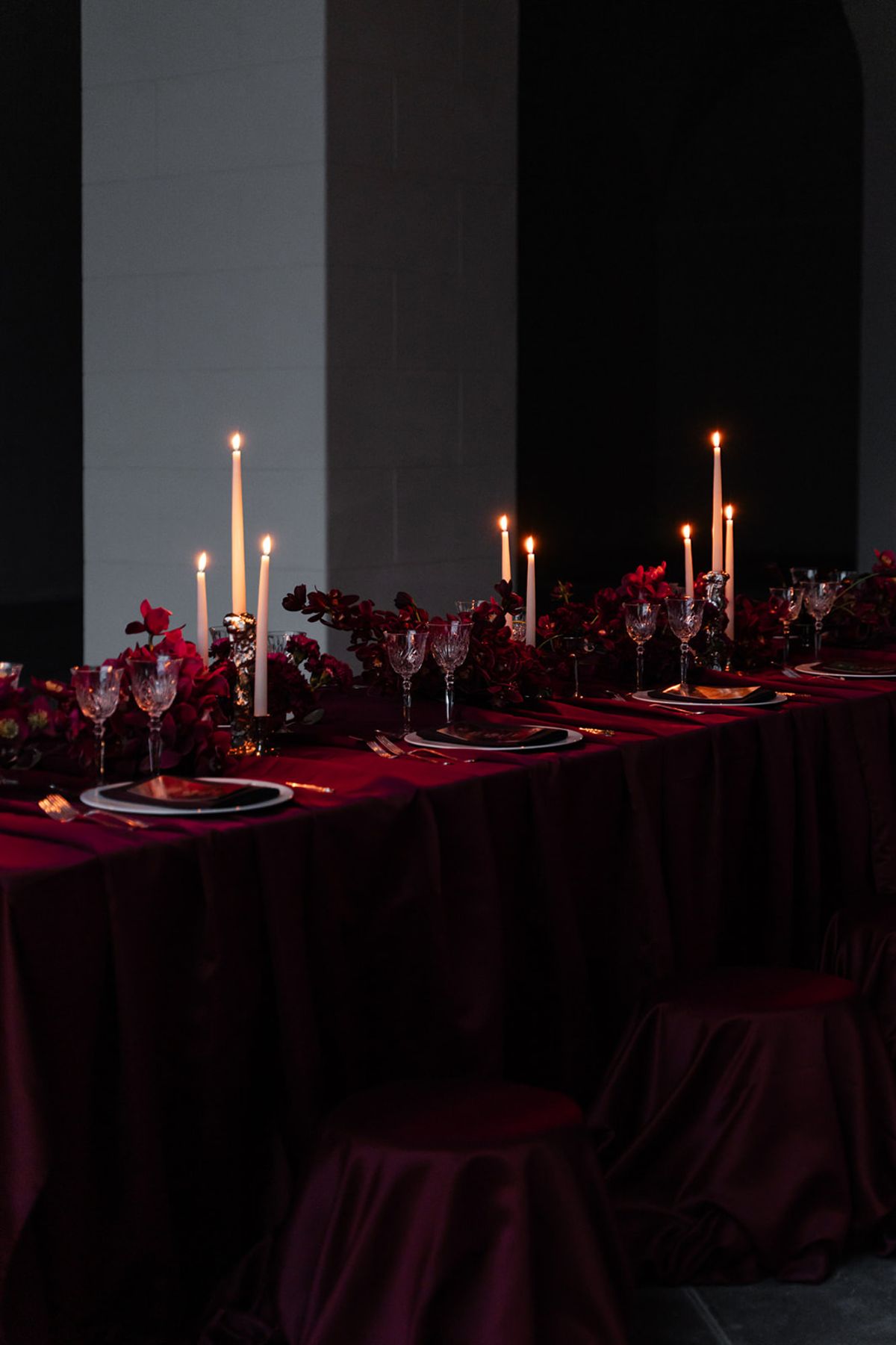 Candlelit reception table with burgundy linen and red florals at Domaine des Halles