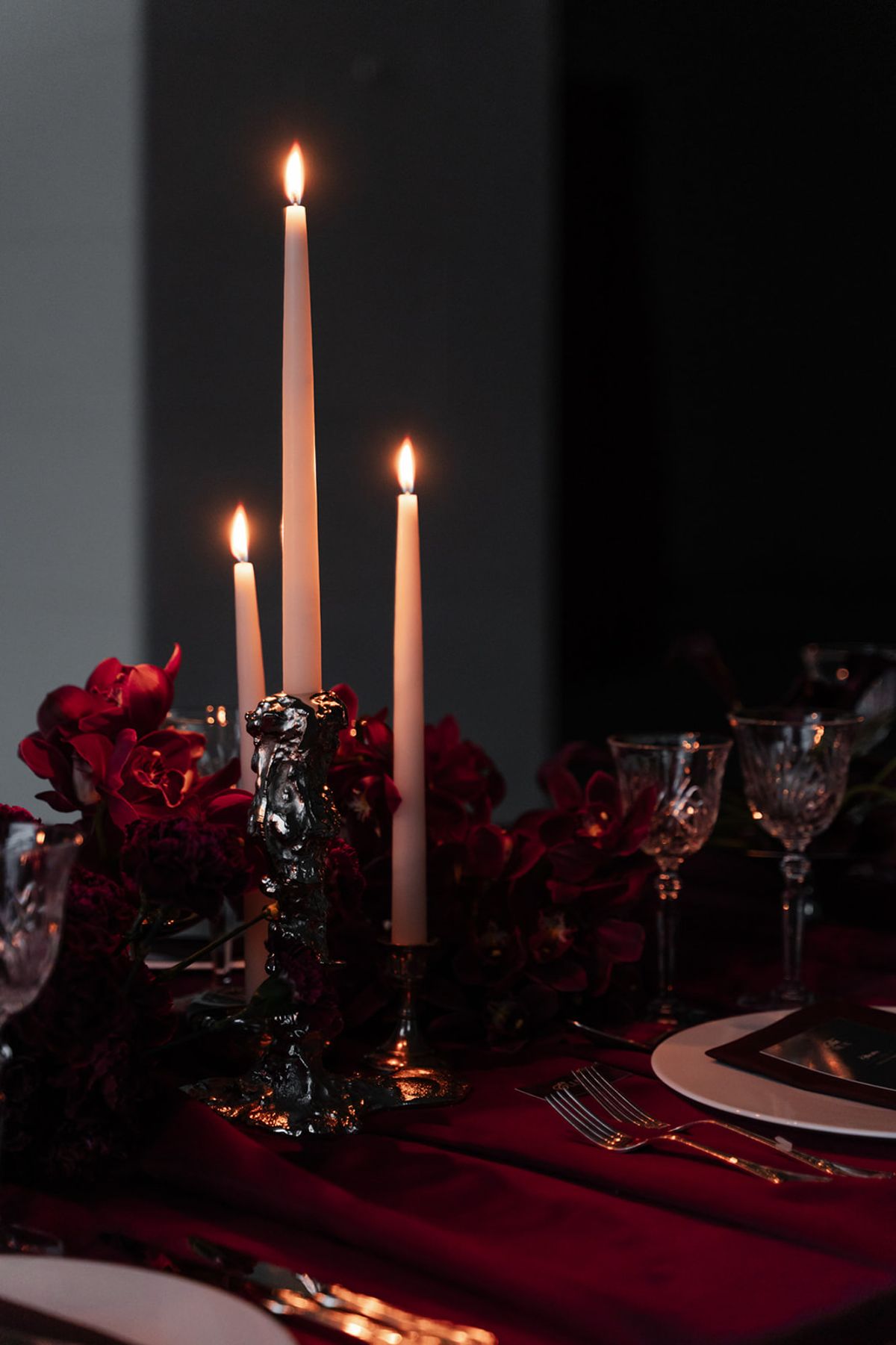 Ornate candelabra with tapered candles and red orchids at Domaine des Halles