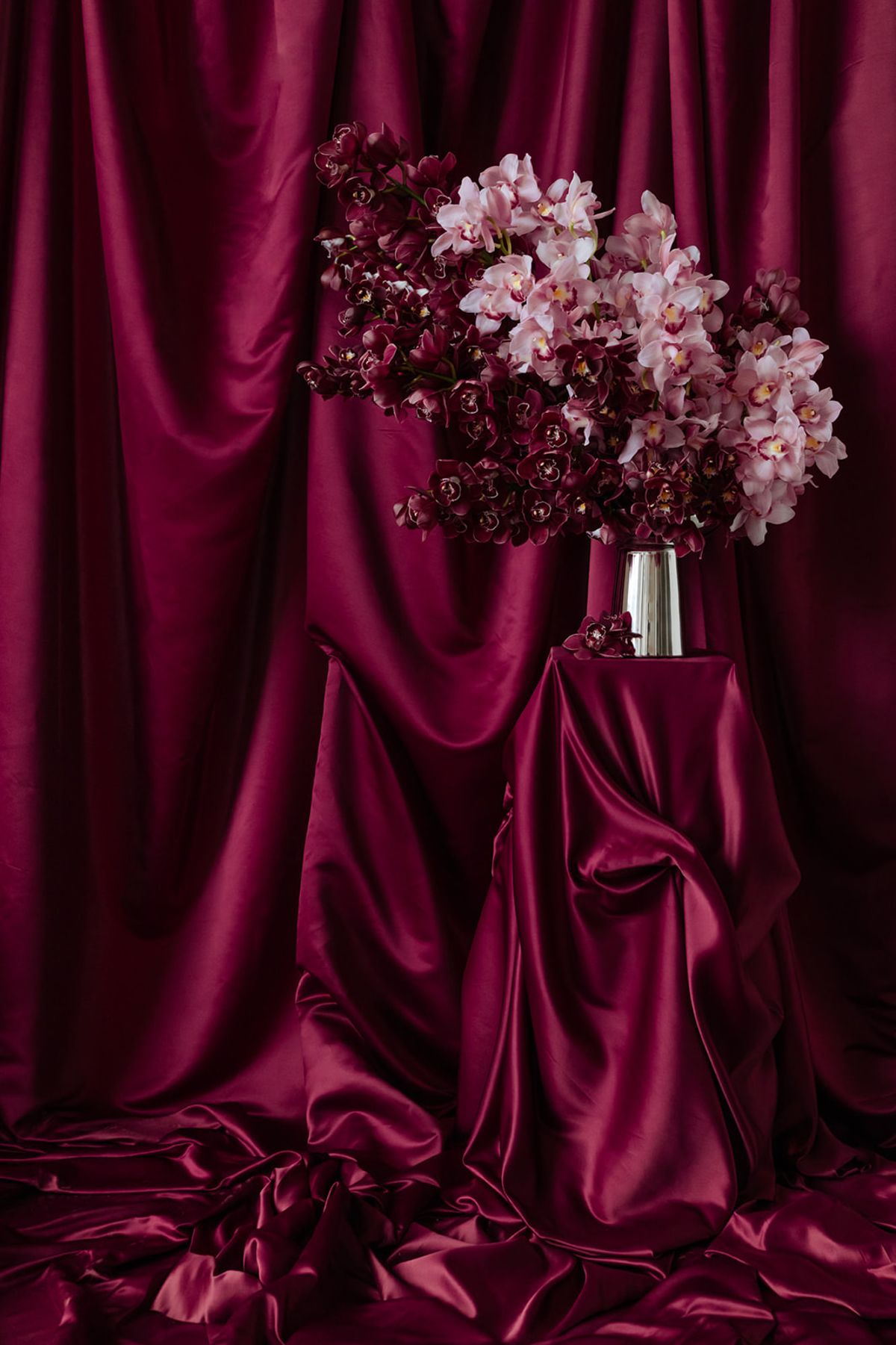 Ceremony orchid arrangement on draped magenta satin at Domaine des Halles