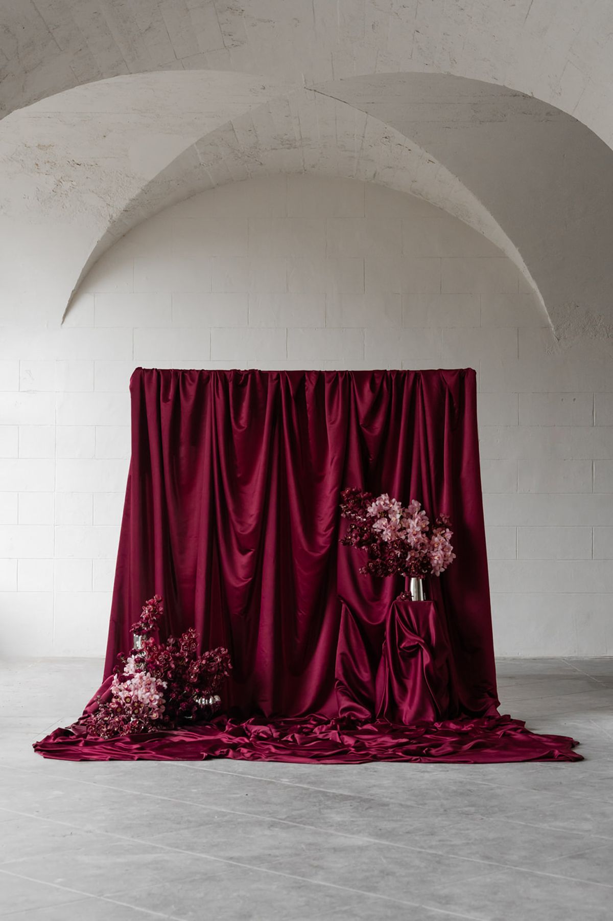 Ceremony backdrop with magenta satin draping under vaulted arch at Domaine des Halles