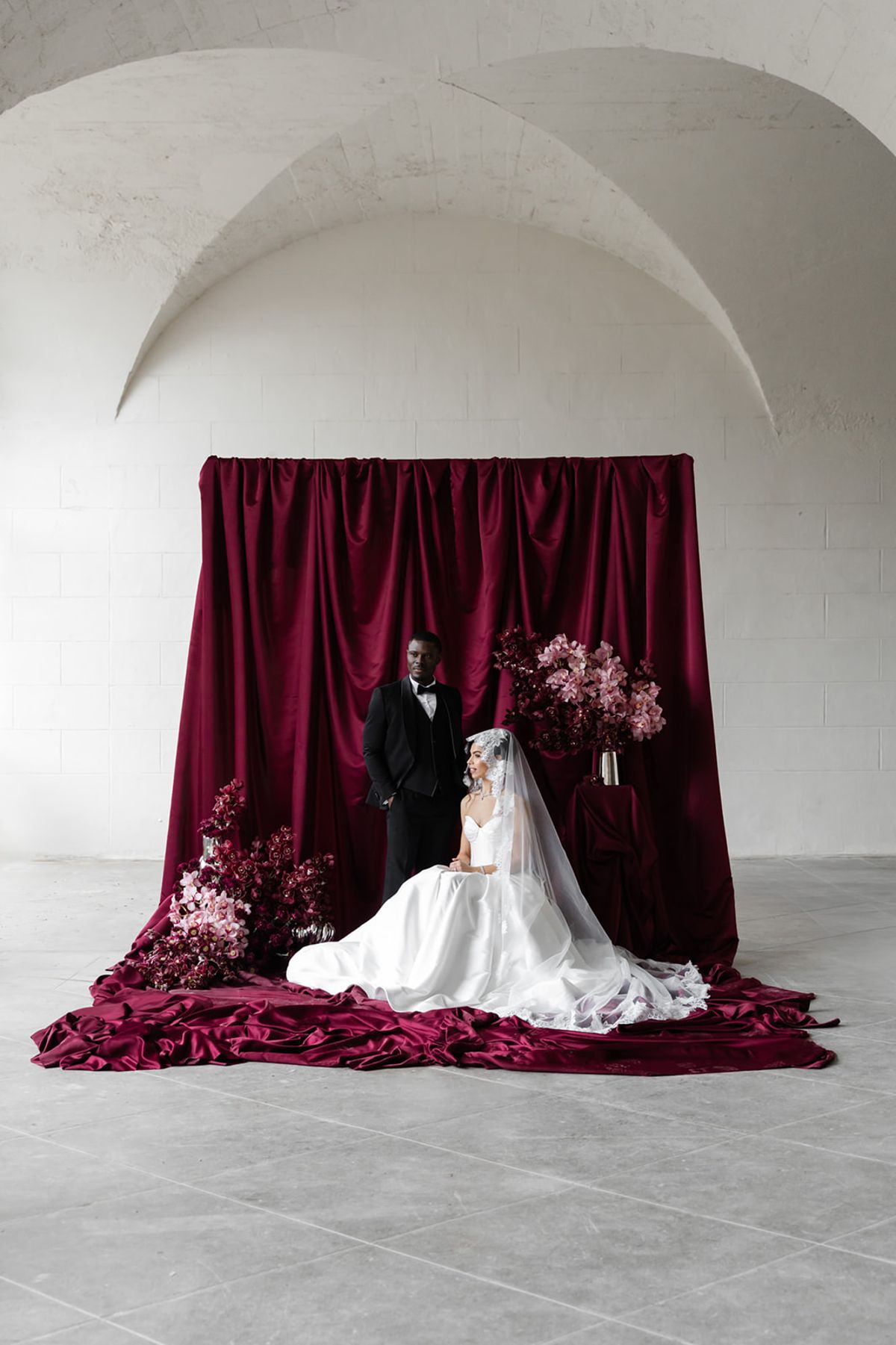 Formal couple portrait against magenta satin backdrop at Domaine des Halles