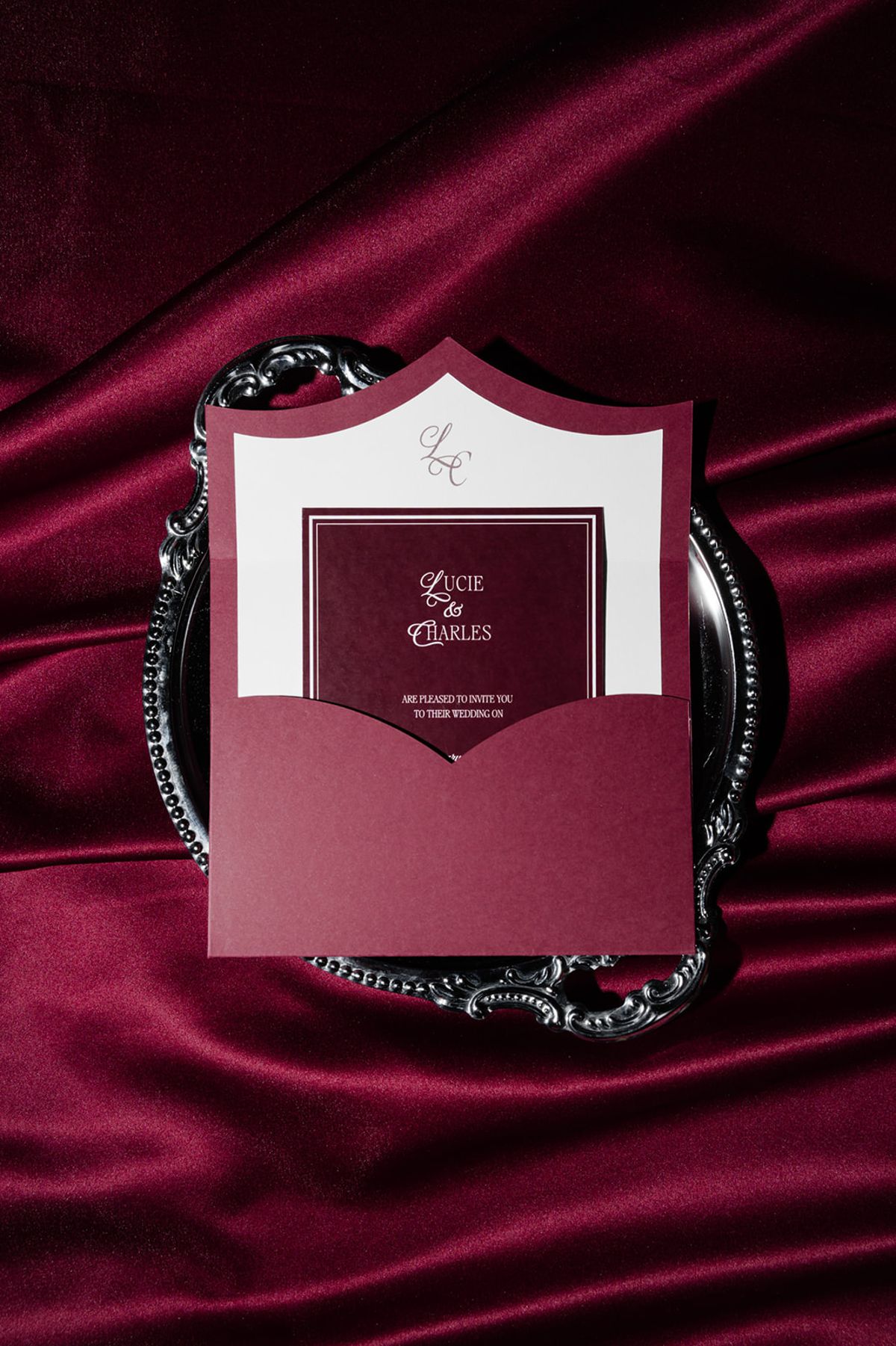 Wedding invitation on silver tray on burgundy satin at Domaine des Halles