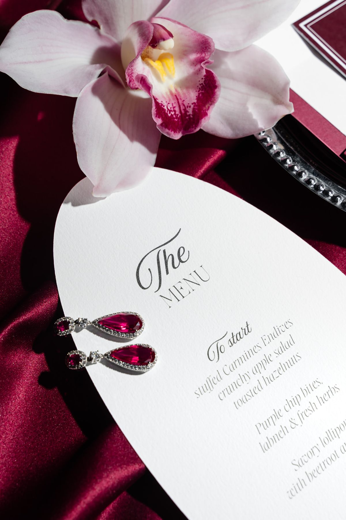 Wedding menu card with ruby earrings and orchid at Domaine des Halles