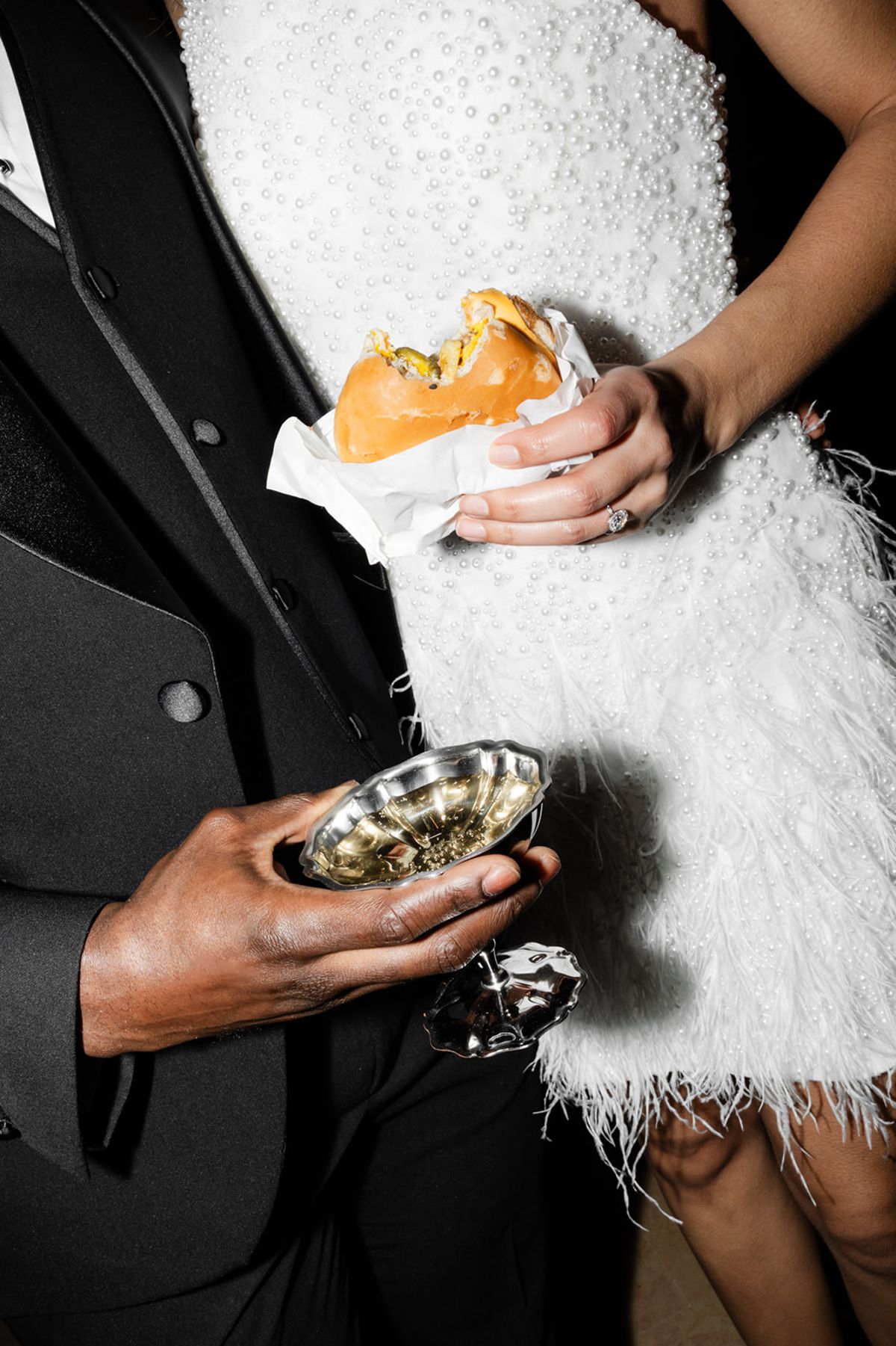 Couple holding burger and champagne cup at Domaine des Halles after-party