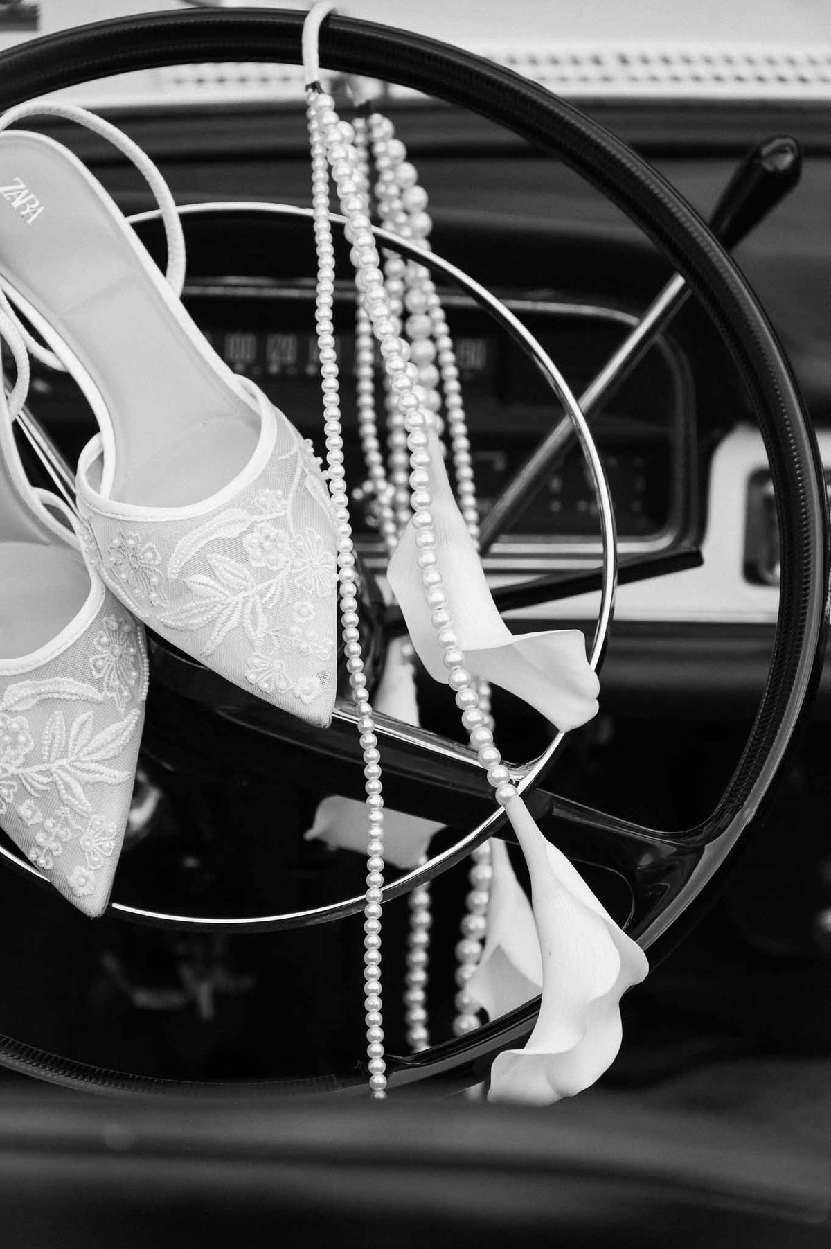 Bridal shoes and pearls on vintage car steering wheel at Chateau d'Hazeville