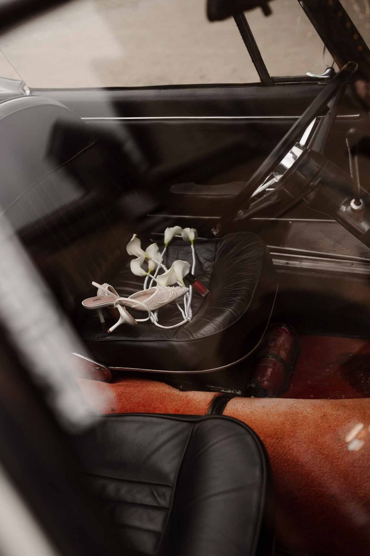 Bridal shoes and calla lilies in vintage car at Chateau d'Hazeville