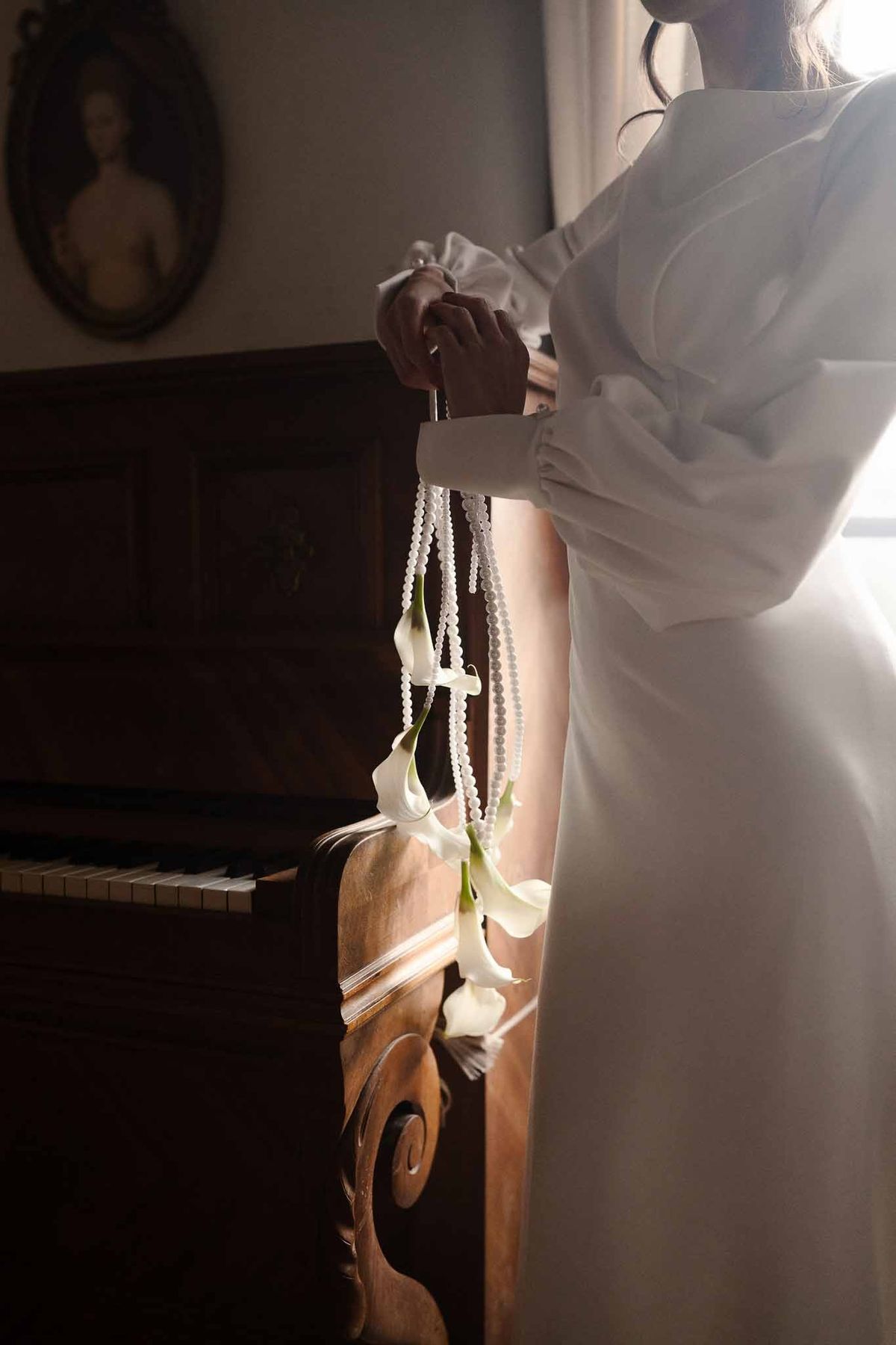 Bride with calla lily bouquet by piano at Chateau d'Hazeville