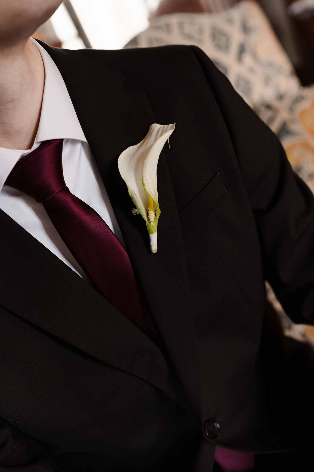 Groom's calla lily boutonniere and burgundy tie at Chateau d'Hazeville